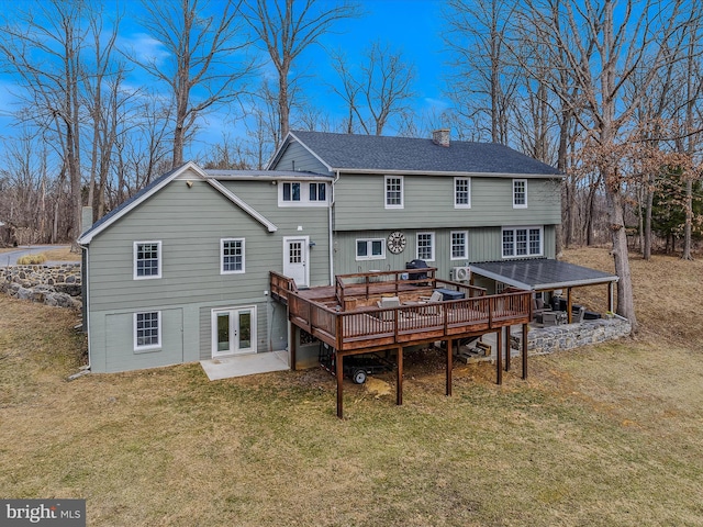 back of property with a shingled roof, a lawn, a chimney, and a wooden deck