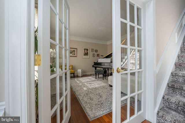 doorway featuring baseboards, ornamental molding, wood finished floors, stairs, and french doors