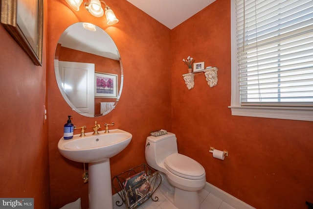 bathroom with baseboards, a sink, toilet, and tile patterned floors