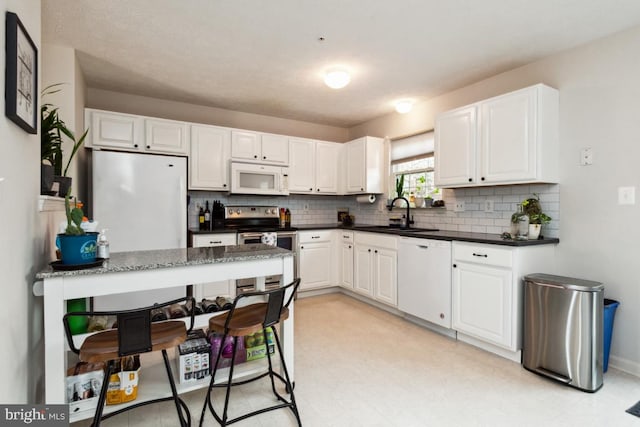 kitchen with white cabinets, white appliances, and a sink