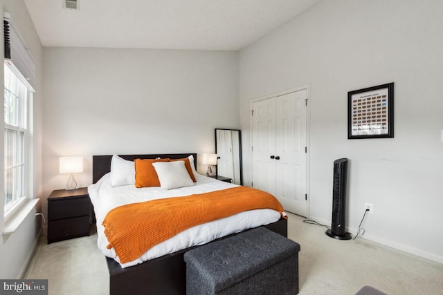 bedroom featuring baseboards, multiple windows, light carpet, and a closet