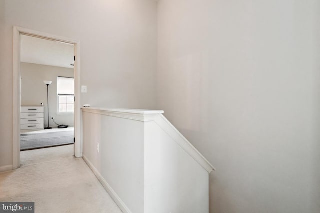 corridor with an upstairs landing, carpet flooring, and baseboards