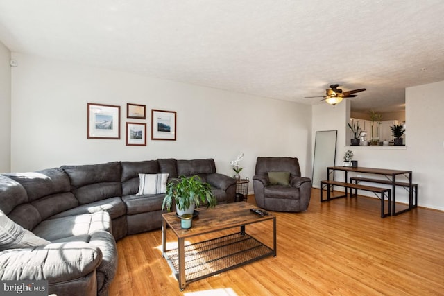 living room featuring a textured ceiling, light wood-style flooring, and a ceiling fan