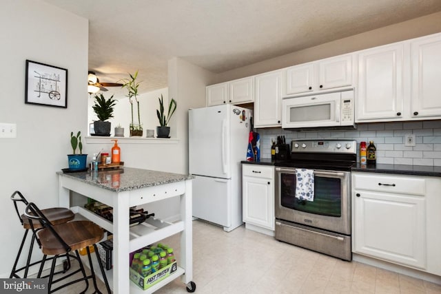 kitchen with backsplash, white cabinets, white appliances, and dark stone countertops