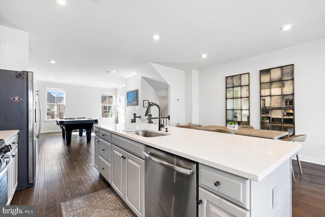 kitchen with a sink, recessed lighting, dark wood-style floors, stainless steel appliances, and a kitchen island with sink