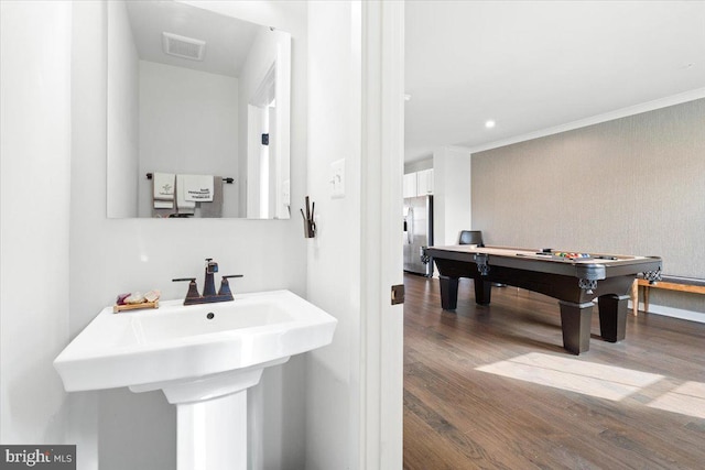 bathroom featuring visible vents, ornamental molding, a sink, wood finished floors, and pool table