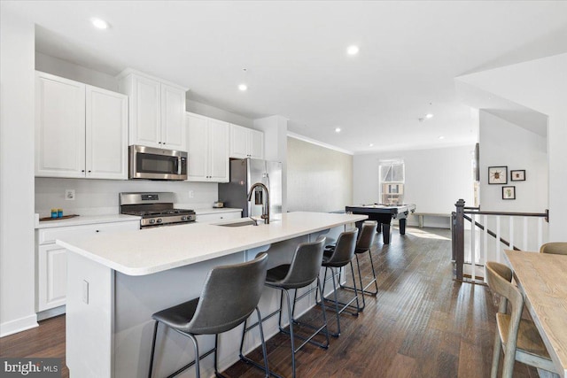 kitchen with an island with sink, a sink, dark wood finished floors, white cabinetry, and stainless steel appliances