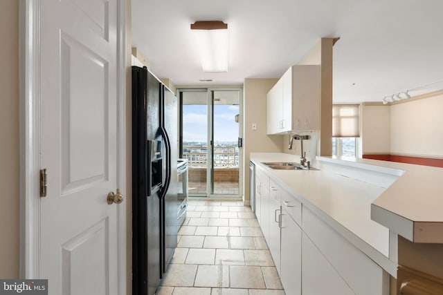 kitchen with floor to ceiling windows, light countertops, black refrigerator with ice dispenser, white cabinetry, and a sink