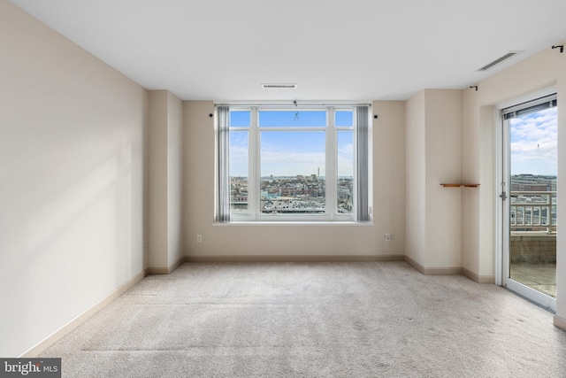 unfurnished room with a wealth of natural light, carpet flooring, and visible vents