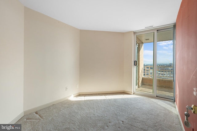 unfurnished room featuring expansive windows, carpet, visible vents, and baseboards