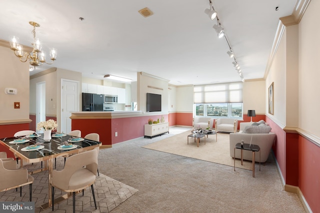 living area with visible vents, ornamental molding, carpet flooring, track lighting, and a chandelier