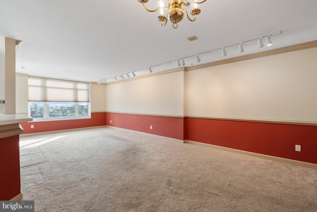 unfurnished room featuring a chandelier, carpet flooring, and baseboards