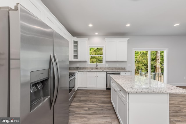 kitchen featuring white cabinets, a kitchen island, appliances with stainless steel finishes, a sink, and recessed lighting