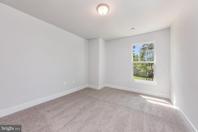 carpeted spare room featuring visible vents and baseboards