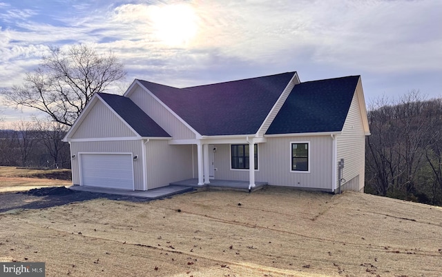 view of front of home featuring a shingled roof, an attached garage, and dirt driveway