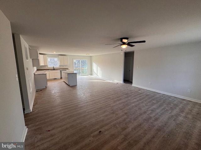 unfurnished living room featuring dark wood finished floors, a ceiling fan, and baseboards