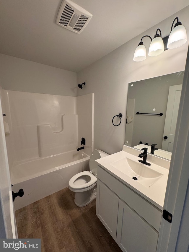 full bath featuring bathtub / shower combination, toilet, wood finished floors, vanity, and visible vents