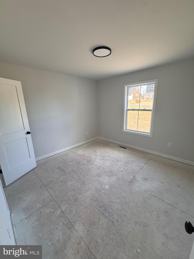 unfurnished room with concrete flooring and baseboards