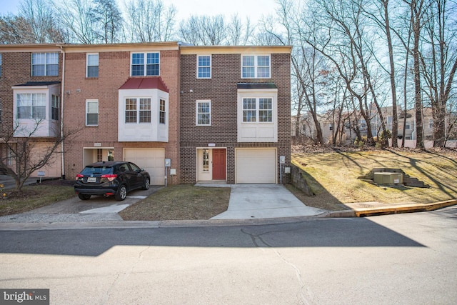 multi unit property featuring a garage, brick siding, and driveway