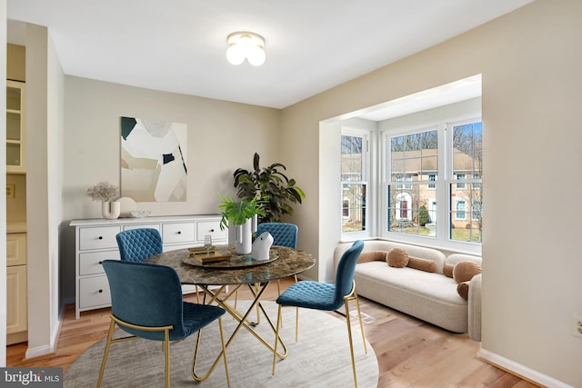 dining space featuring light wood-type flooring and baseboards