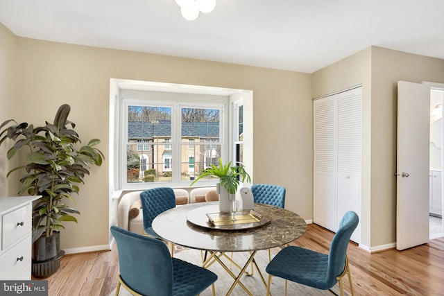 dining space with light wood-style flooring and baseboards