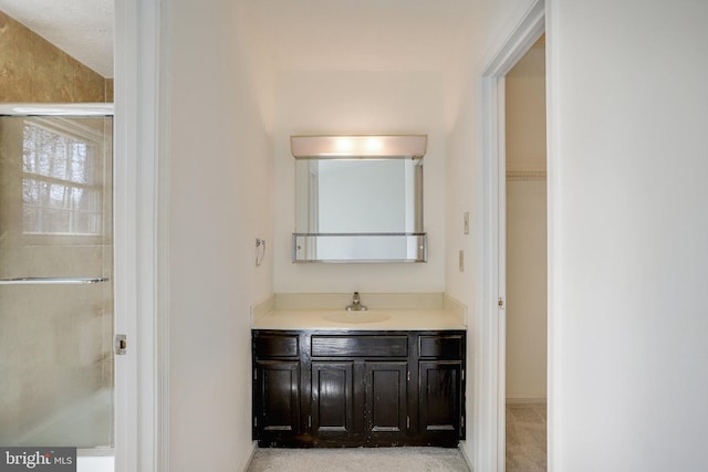 full bathroom with a shower stall, vanity, and a walk in closet