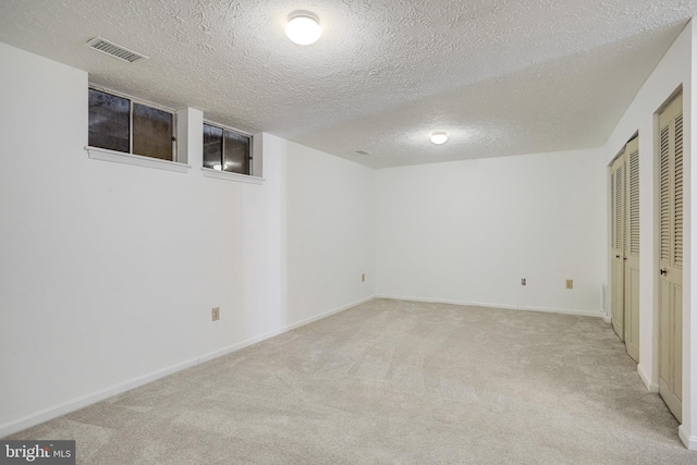 finished basement with carpet floors, baseboards, visible vents, and a textured ceiling