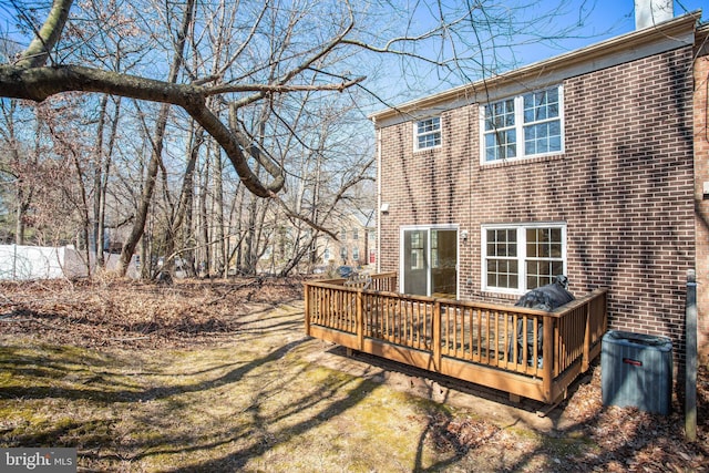 back of house with a chimney, brick siding, a lawn, and a deck