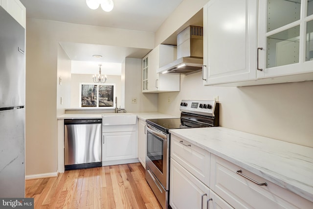 kitchen featuring white cabinets, wall chimney exhaust hood, stainless steel appliances, and light wood-style flooring