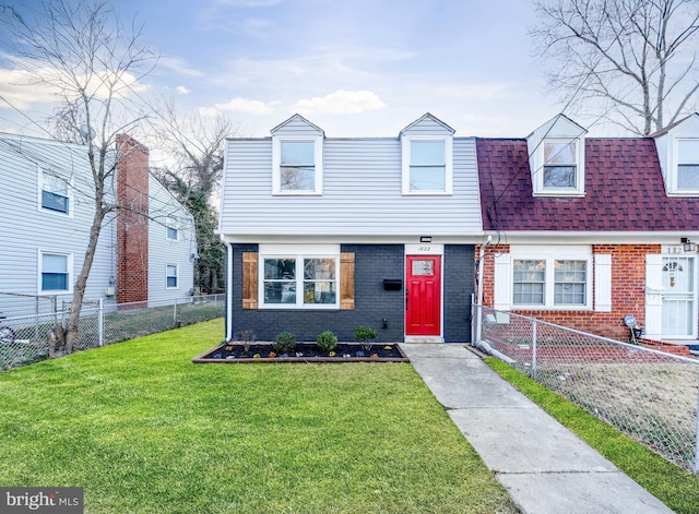 view of front facade with a front lawn, a shingled roof, fence private yard, and brick siding