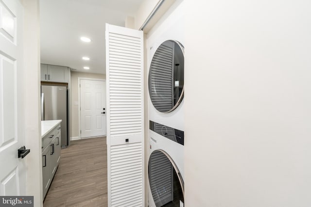 laundry room featuring stacked washer and dryer, light wood-type flooring, laundry area, and recessed lighting