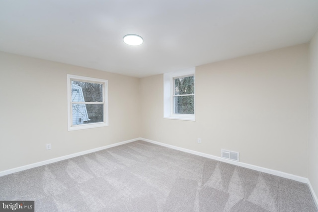 spare room with a wealth of natural light, carpet, visible vents, and baseboards