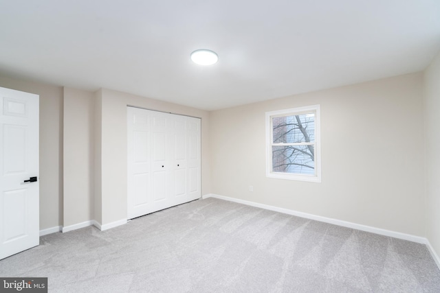 unfurnished bedroom featuring carpet, baseboards, and a closet