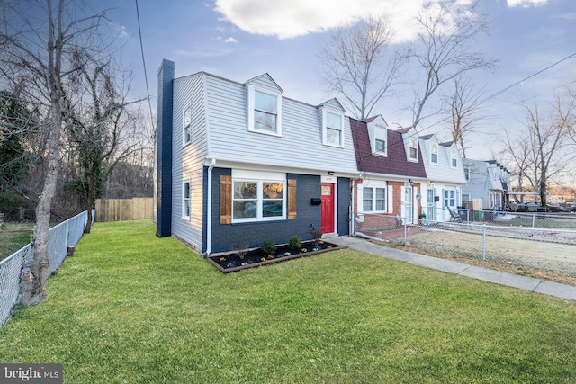 view of front of property featuring a front yard, fence private yard, a chimney, and brick siding