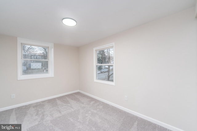 carpeted spare room with a healthy amount of sunlight and baseboards