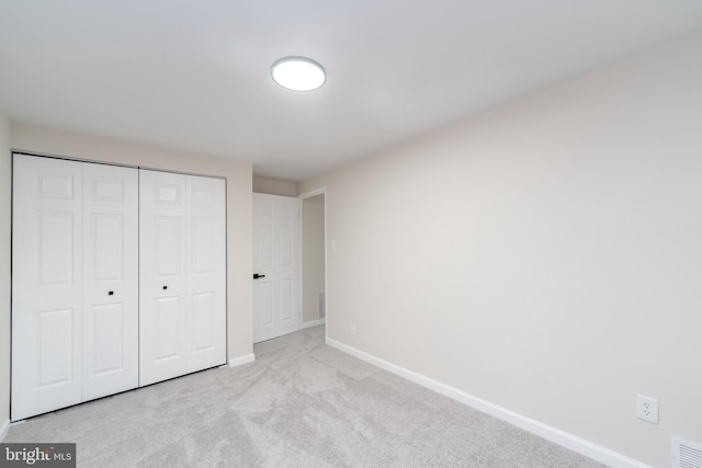 unfurnished bedroom with a closet, carpet flooring, visible vents, and baseboards