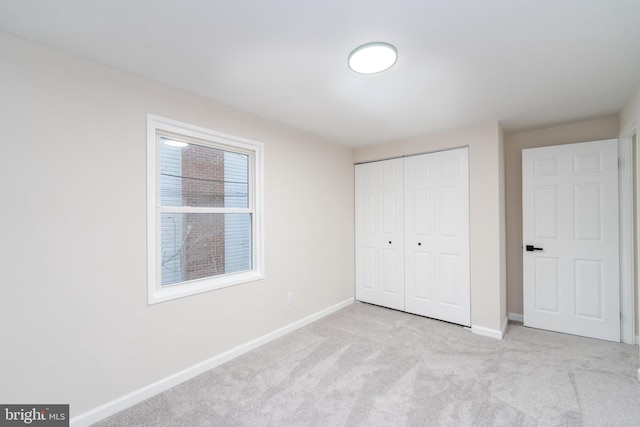 unfurnished bedroom with a closet, carpet flooring, and baseboards