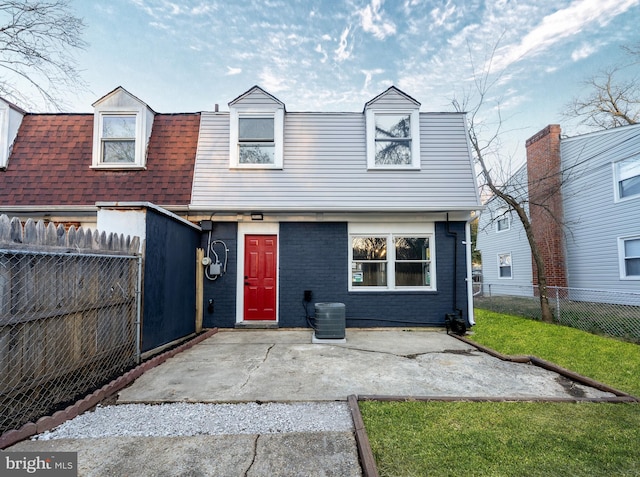 view of front of home featuring a patio, a fenced backyard, central air condition unit, a front yard, and brick siding