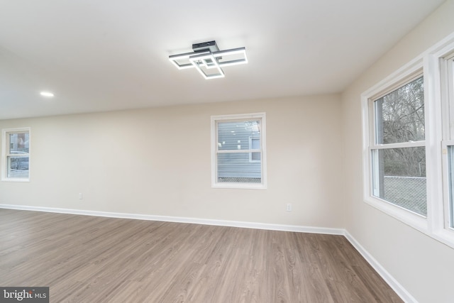 spare room with baseboards, wood finished floors, and recessed lighting