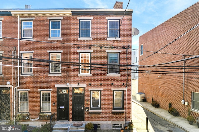 view of property featuring brick siding and a chimney