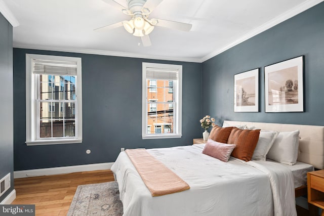 bedroom with visible vents, baseboards, wood finished floors, and ornamental molding