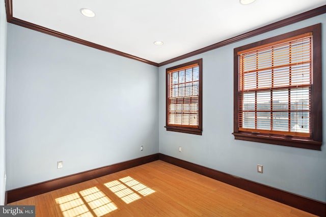 empty room featuring ornamental molding, light wood-style floors, plenty of natural light, and baseboards