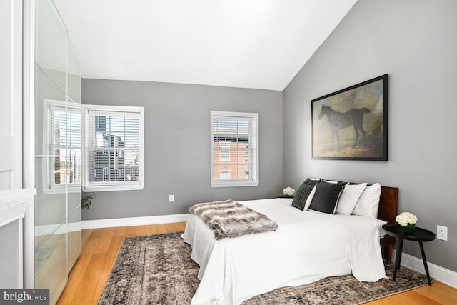 bedroom with vaulted ceiling, baseboards, and wood finished floors