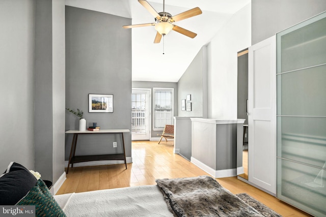 bedroom with vaulted ceiling, light wood-type flooring, a ceiling fan, and baseboards