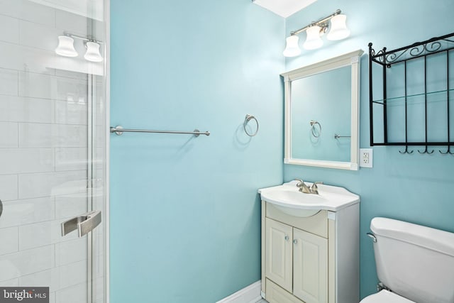 bathroom with a tile shower, vanity, and toilet