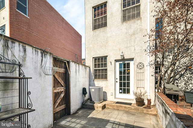 doorway to property with central air condition unit and stucco siding