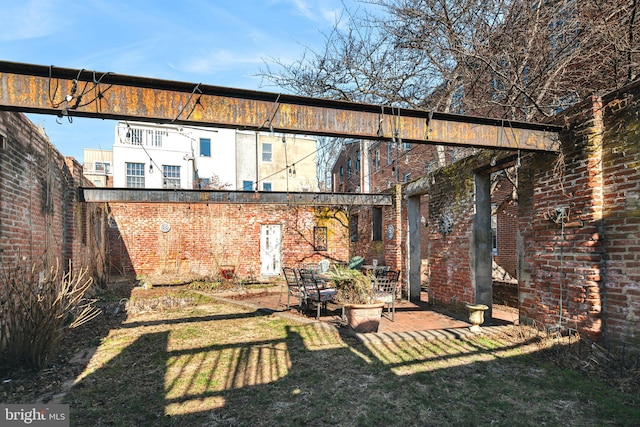 rear view of property featuring a patio area, brick siding, and a lawn