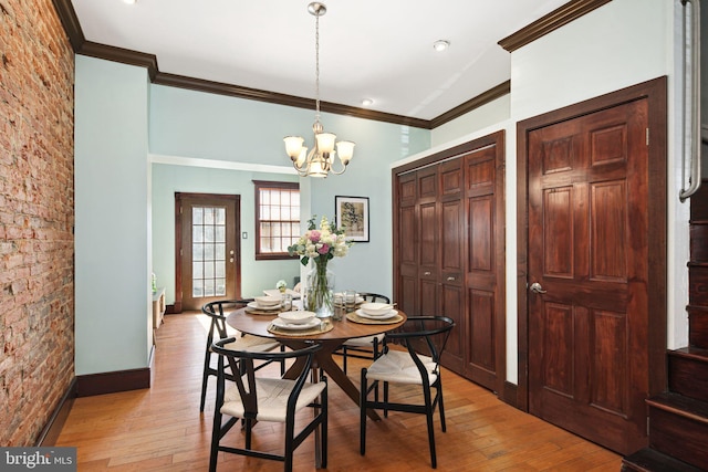 dining space featuring a chandelier, baseboards, crown molding, and light wood finished floors