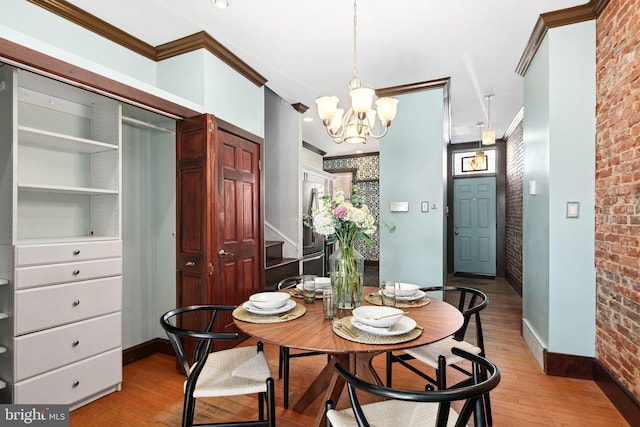 dining space with brick wall, ornamental molding, light wood-type flooring, and baseboards