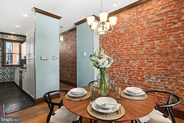 dining room with dark wood-style floors, crown molding, an inviting chandelier, brick wall, and baseboards